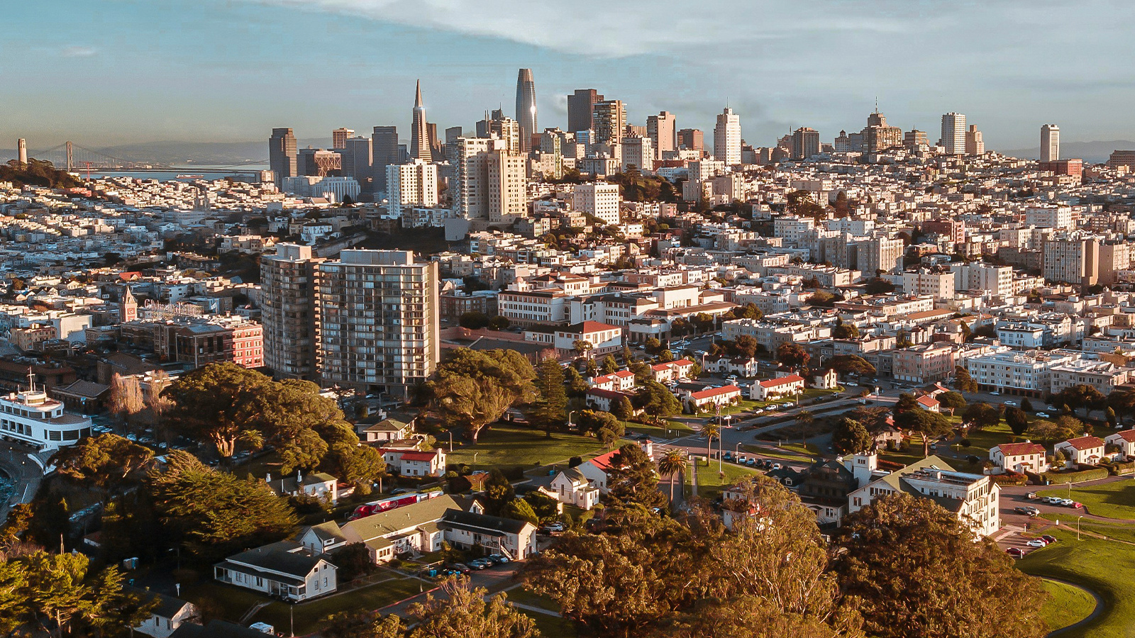 Skyline of San Francisco with the Golden Gate bridge deep in the background.