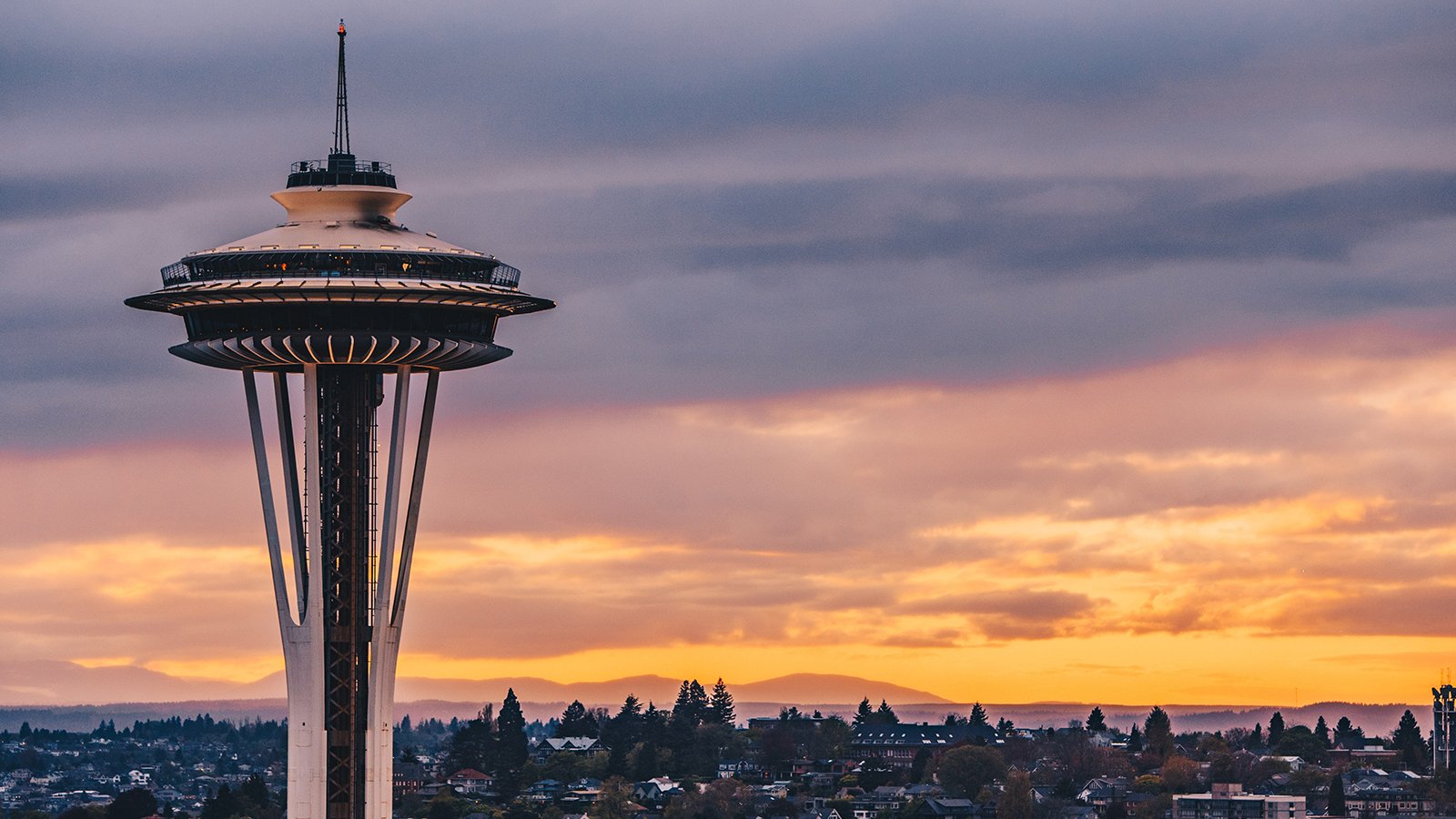 A close up of the Space Needle with the Seattle landscape in the background.