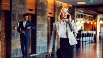 Happy businesswoman on a business trip walking in the hall of the hotel and talking on the phone