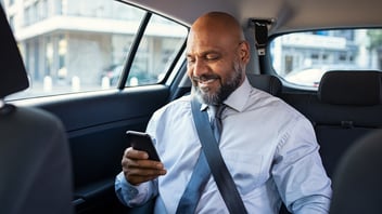 Business man using his smartphone in the backseat of a car.