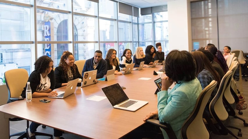 A group of people sitting around a table in a meeting room.
