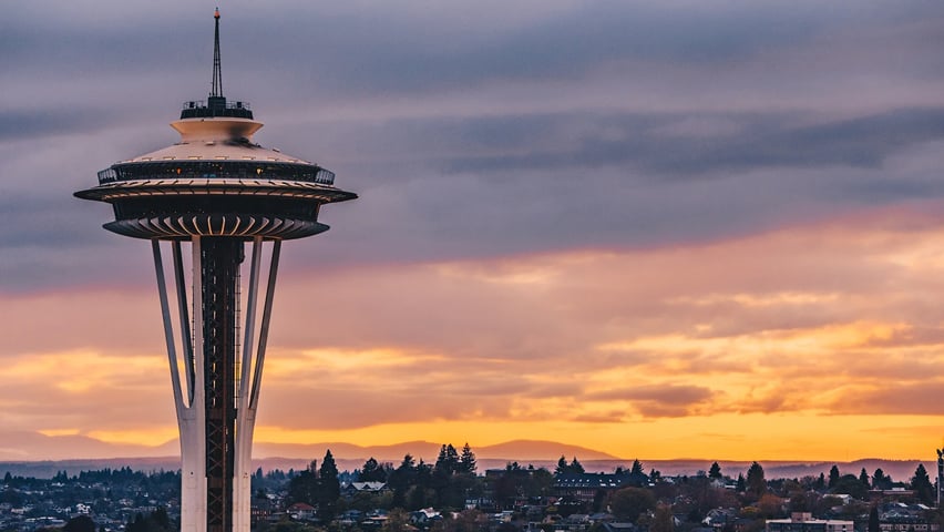 A close up of the Space Needle with the Seattle landscape in the background.