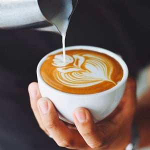 Pouring cream into coffee mug