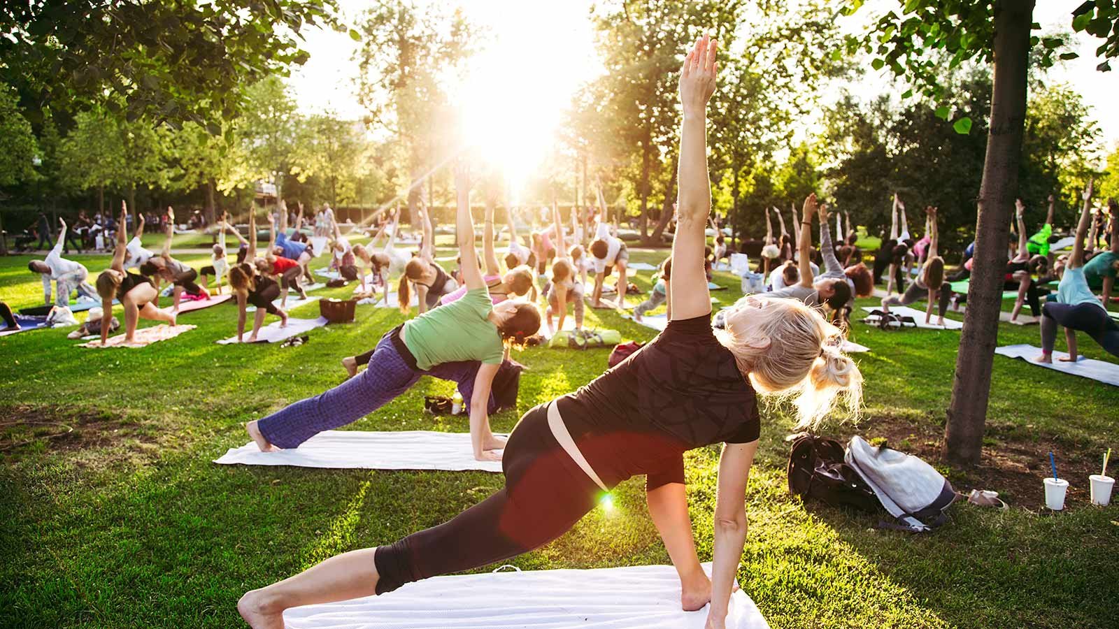 Adults attending a yoga class outside in park