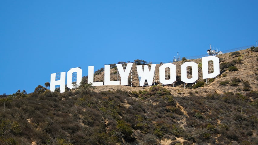 Famous white Hollywood sign on hillside against clear blue sky in Los Angeles.