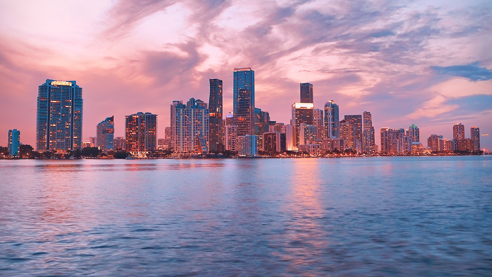 Miami skyline at sunset with the ocean in the foreground.