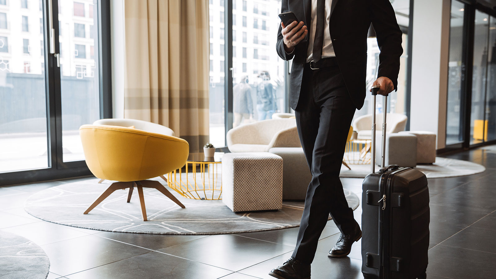 Man walks with luggage through hotel lobby